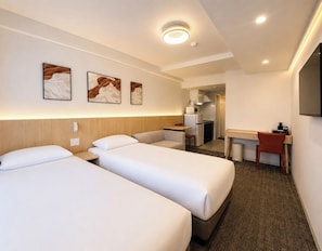 Quarto de hotel com duas camas, uma escrivaninha, uma cadeira, micro-ondas e televisão.