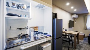 A compact kitchenette with a sink, stove, and storage shelves.