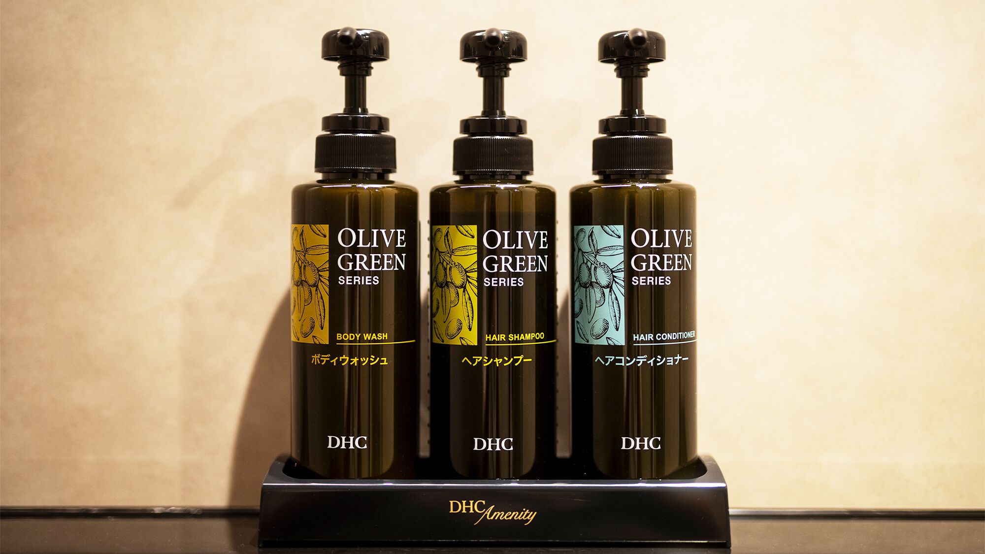Three bottles of Olive Green Series products on a black stand.