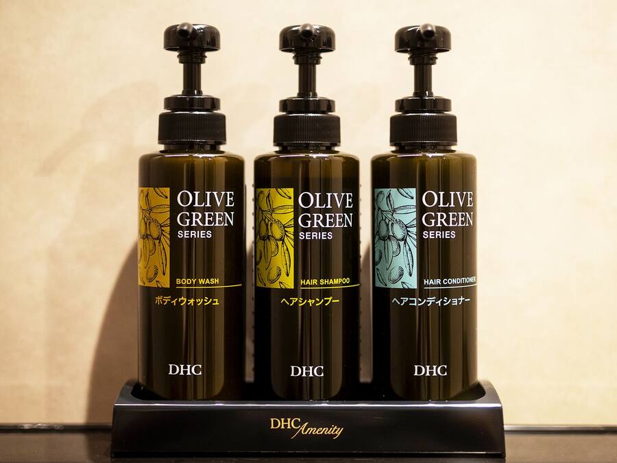 Three bottles of Olive Green Series products on a black stand.