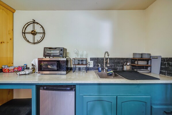 Una cocina equipada con microondas, tostadora, lavaplatos y armarios.