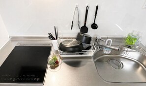 A kitchen with a built-in stove, a sink, and various utensils hanging above it. - Casa G.S. PortVilla (Osaka-shi minato-ku chiko)
