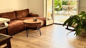 A living room with a brown sofa, a round wooden coffee table, and a dining table with chairs. - Charming apartment A stay in the heart of the Mediterranean 2 steps from the beaches (La Ciotat)