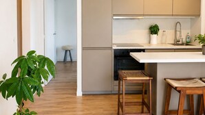 A modern kitchen with wooden flooring, a built-in oven, and a white countertop. - Charming apartment A stay in the heart of the Mediterranean 2 steps from the beaches (La Ciotat)