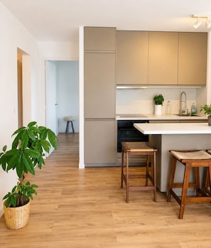 Eine moderne Küche mit Holzboden, einem eingebauten Ofen und einer weißen Arbeitsplatte.