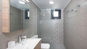 Ein modernes Badezimmer mit einem großen Spiegel, einem Waschbecken, einer Toilette und einer Duschkabine.