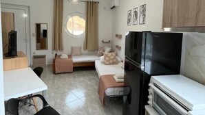 Ein kompakter Wohnraum mit Küchenzeile, Essbereich und Sitzecke mit Sofa und kleinem Tisch.