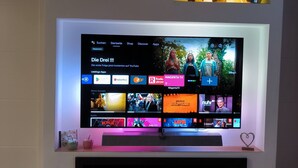 Un mueble moderno de entretenimiento con un televisor de pantalla plana que muestra un canal de YouTube, rodeado de objetos decorativos y una chimenea.