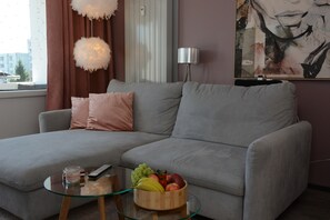 A modern living room with a grey sofa, a glass coffee table, a fruit bowl, and a painting on the wall. - Stylish 4-Star Apartment for 4 Guests, Fast Wi-Fi Included (Goslar)