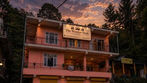 Un edificio de dos pisos con balcones, un cartel que dice 'The Wooden Nook Chail' y escaparates para 'Ambuja KAWACH', 'Ambuja COOL WALLS' y 'Ambuja Cement'.