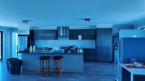 Une cuisine moderne dotée d’un îlot central, de tabourets en bois et d’une cuisinière intégrée.