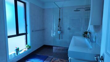 A bathroom with a shower, sink, and window.