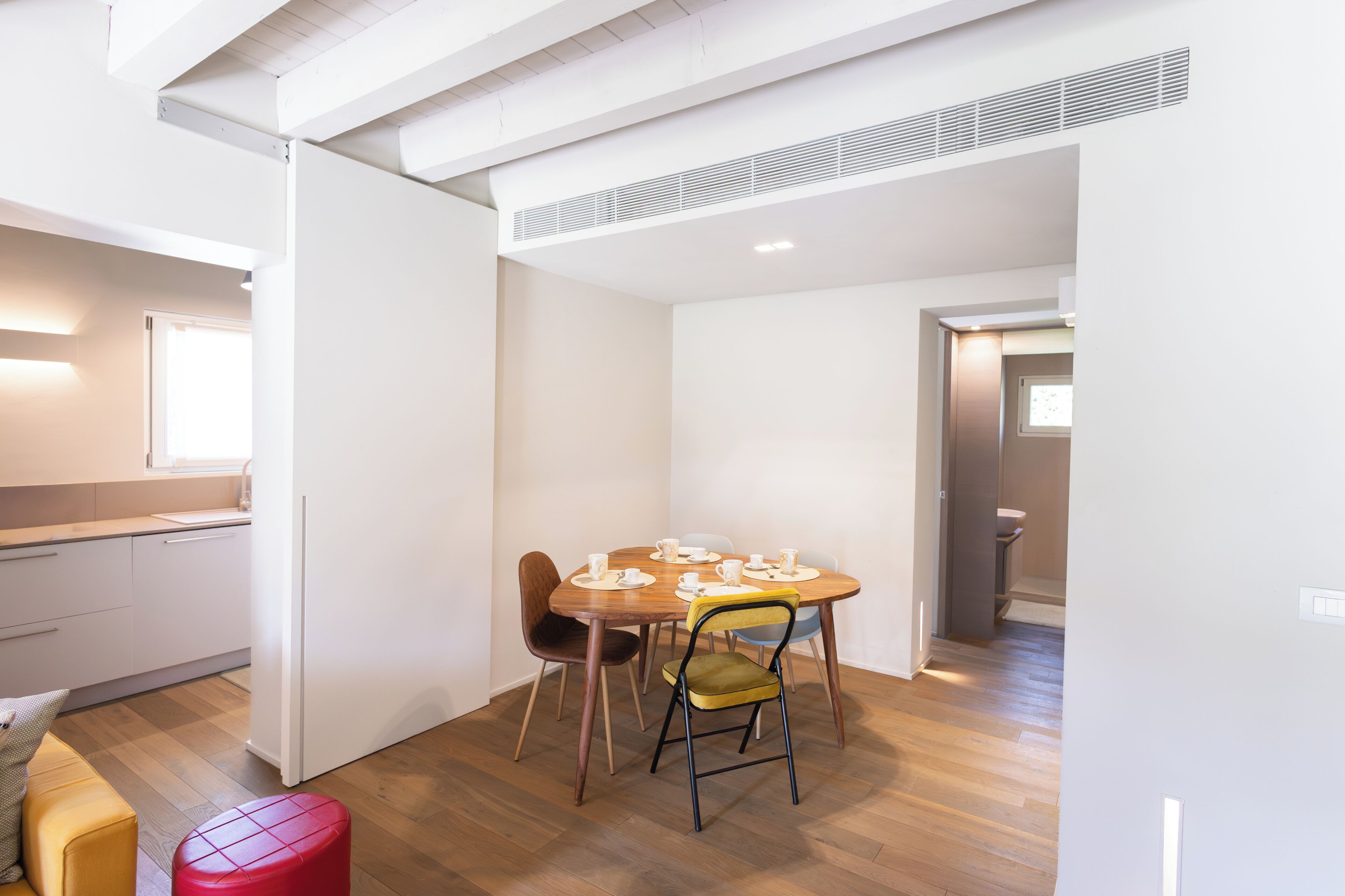 Un espace de vie compact comprenant un coin cuisine, un espace repas avec une table ronde et des chaises, et une salle de bain visible.
