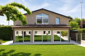 A modern house with a covered patio, large windows, and a well-maintained lawn. - Casa Cordigero - Adults Only (Ponti sul Mincio)
