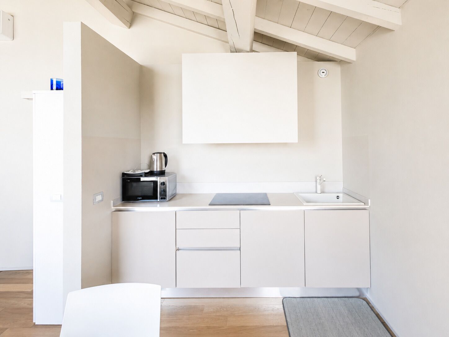 A compact kitchen with a microwave, kettle, and sink.