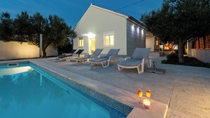 A modern house with a swimming pool, lounge chairs, and candles. - Olive House Pool & Garden (Zemunik Donji)