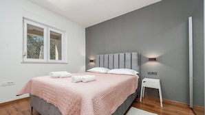 A bedroom with a bed, bedside tables, a window, and a wall-mounted light fixture. - Olive House Pool & Garden (Zemunik Donji)