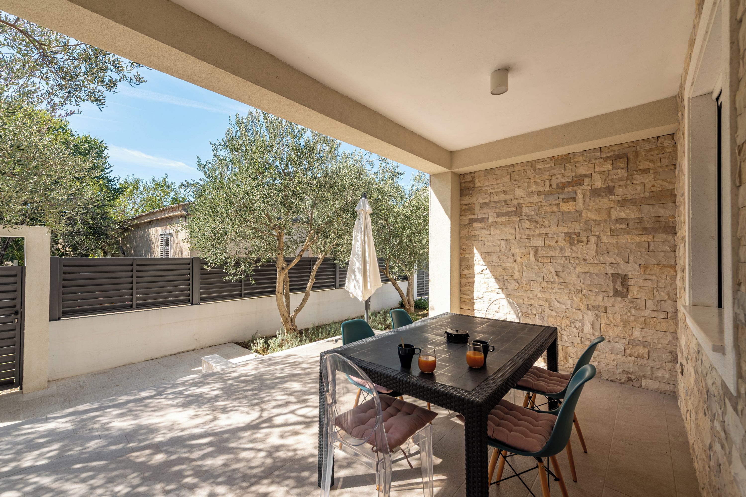 An outdoor patio with a table, chairs, and a stone wall.