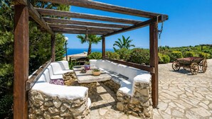 A stone patio with a pergola, outdoor seating, and a view of the sea. - Villa Poseidon - Executive Suite In Zante w/Pool (Skinaria)