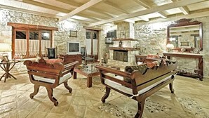 A rustic interior with stone walls, wooden furniture, a fireplace, and a television. - Villa Poseidon - Master Suite In Zante w/Pool (Skinaria)