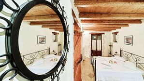 Ein Schlafzimmer mit zwei Betten, Holzbalkendecke und einem Spiegel mit dekorativem Rahmen.