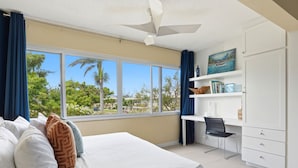 A bedroom with a bed, a desk, and a view of greenery outside. - Hospitality Expert SWE202 - Pool, Beach, Chef (Montego Bay)