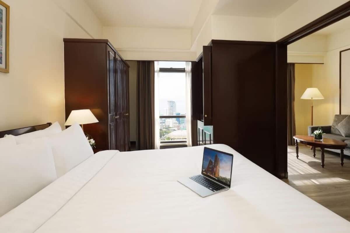 A hotel room with a bed, a laptop, a desk, and a view of the city.