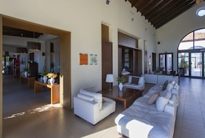 A spacious living area with a sofa set, a coffee table, and a lamp. There are signs on the wall and a view through a large window. - Family Golf Oasis | Disney+, Pool & Sunny Terrace (Murcia)