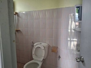 A bathroom with a toilet, a paper towel holder, and a door with a round handle. - Delight Mansion (Bangkok)
