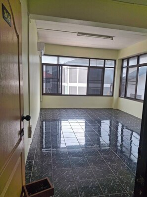 A room with a tiled floor, a door with a number sign, and large windows. - Delight Mansion (Bangkok)