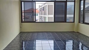 A room with a tiled floor, large windows, and an air conditioning unit on the wall. - Delight Mansion (Bangkok)