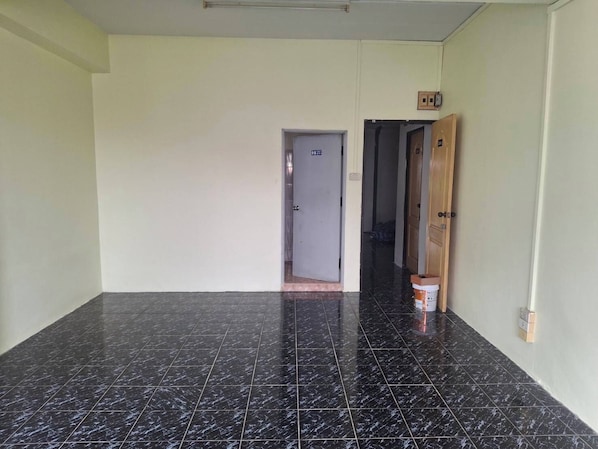 A hallway with black marble flooring, a door with a sign, and a wooden door on the right. - Delight Mansion (Bangkok)