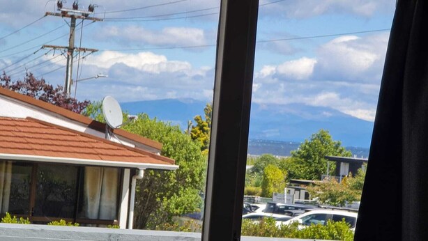 A residential area with a house featuring a satellite dish, a garage, and a view of a parking lot and distant mountains.