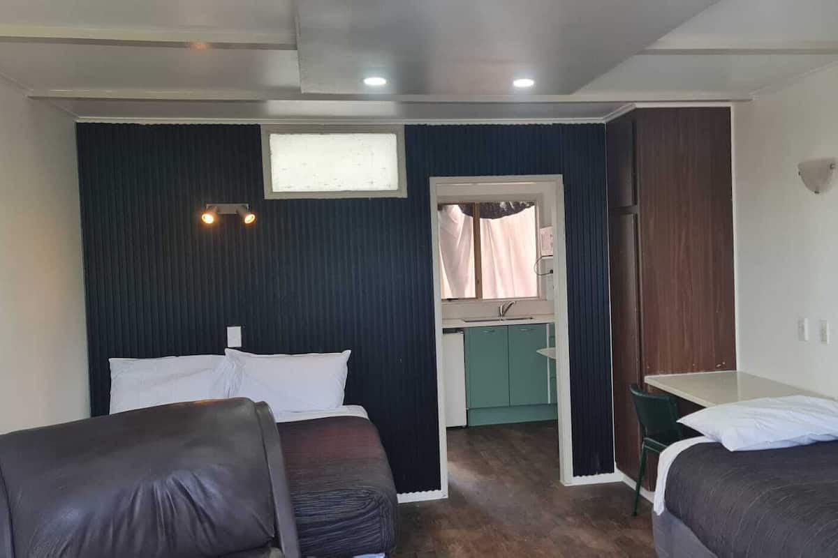 Habitación pequeña con dos camas, un rincón de cocina y una ventana.