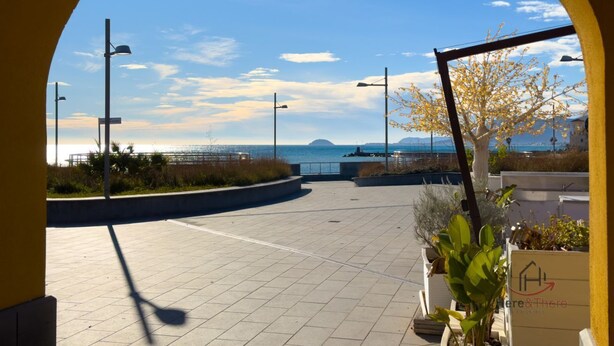 A paved outdoor area with street lamps, a planter with plants, and a view of the sea and distant land. - [Authentic Caruggio] Typical Ligurian Experience (Loano)