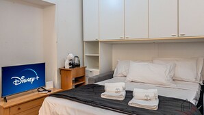 A hotel room with a bed, a TV displaying the Disney+ logo, a wooden nightstand, and a wardrobe. - [Authentic Caruggio] Typical Ligurian Experience (Loano)