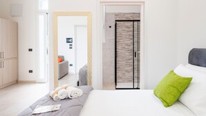 Et moderne hotelværelse med seng, garderobeskab, badeværelse med brusebad og dør til et andet rum.