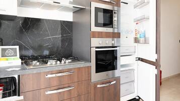A modern kitchen with a gas stove, oven, microwave, and built-in refrigerator.