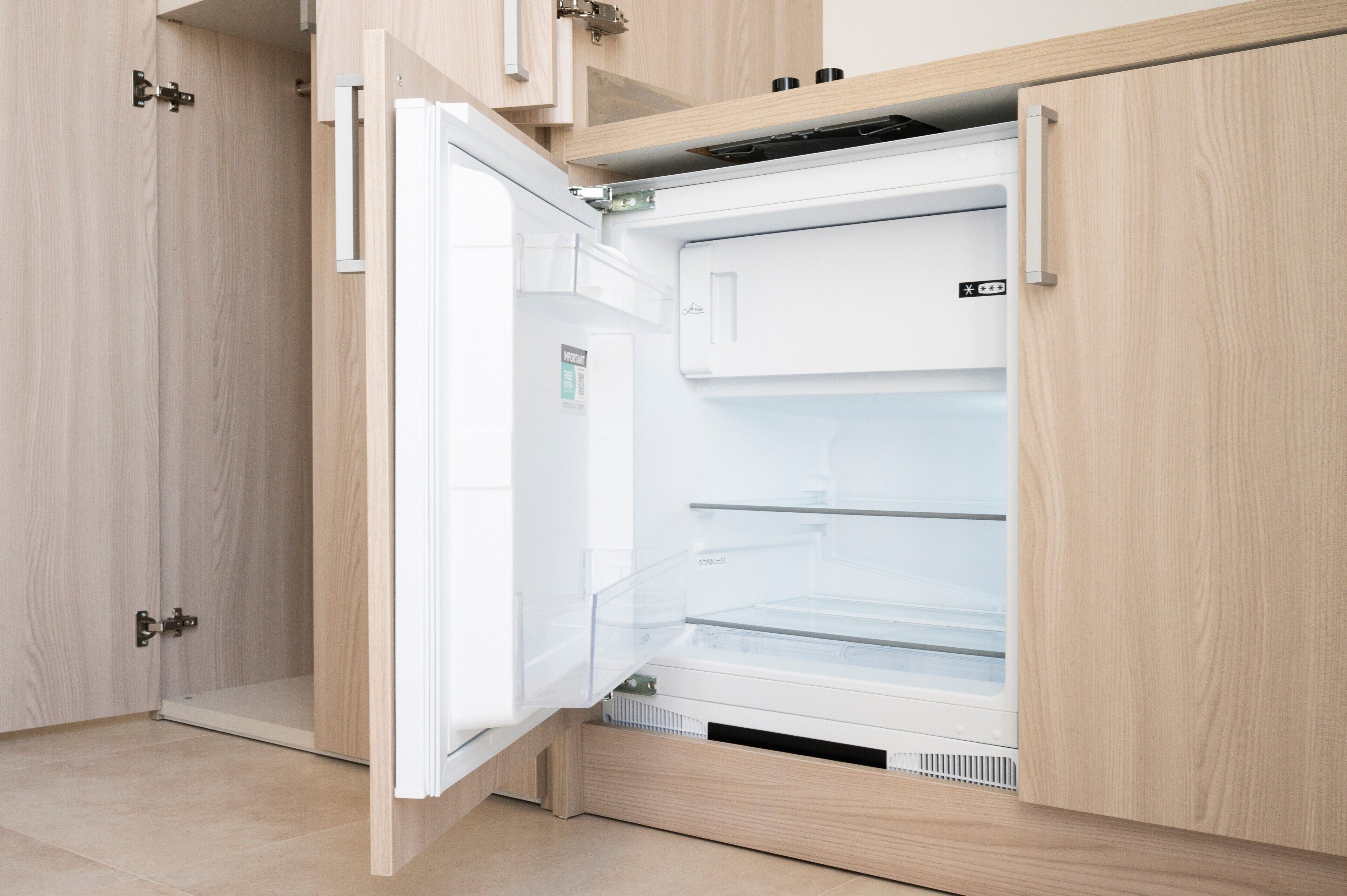 Eine moderne Küche mit Einbaukühlschrank, Holzschränken und einer Edelstahl-Spüle.