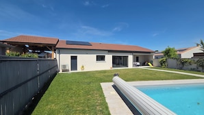 Ein Wohnhaus mit Swimmingpool, überdachter Terrasse und umzäunter Garten.