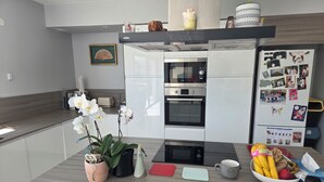 Eine moderne Küche mit Einbauofen, einem Kühlschrank mit Fotos und einer Arbeitsplatte mit einer Obstschüssel und einer Kaffeetasse.
