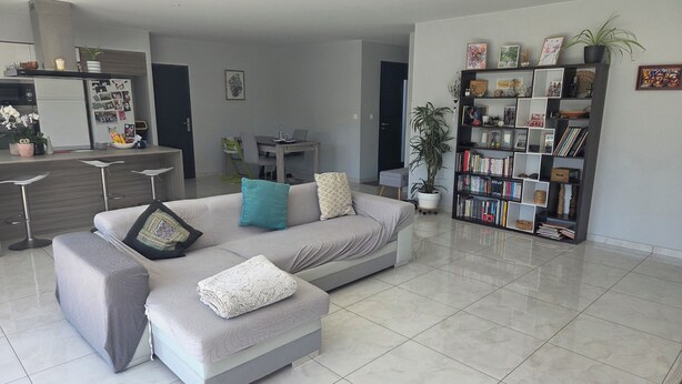 Ein modernes Wohnzimmer mit einer Couch, einem Hocker und einem Bücherregal.