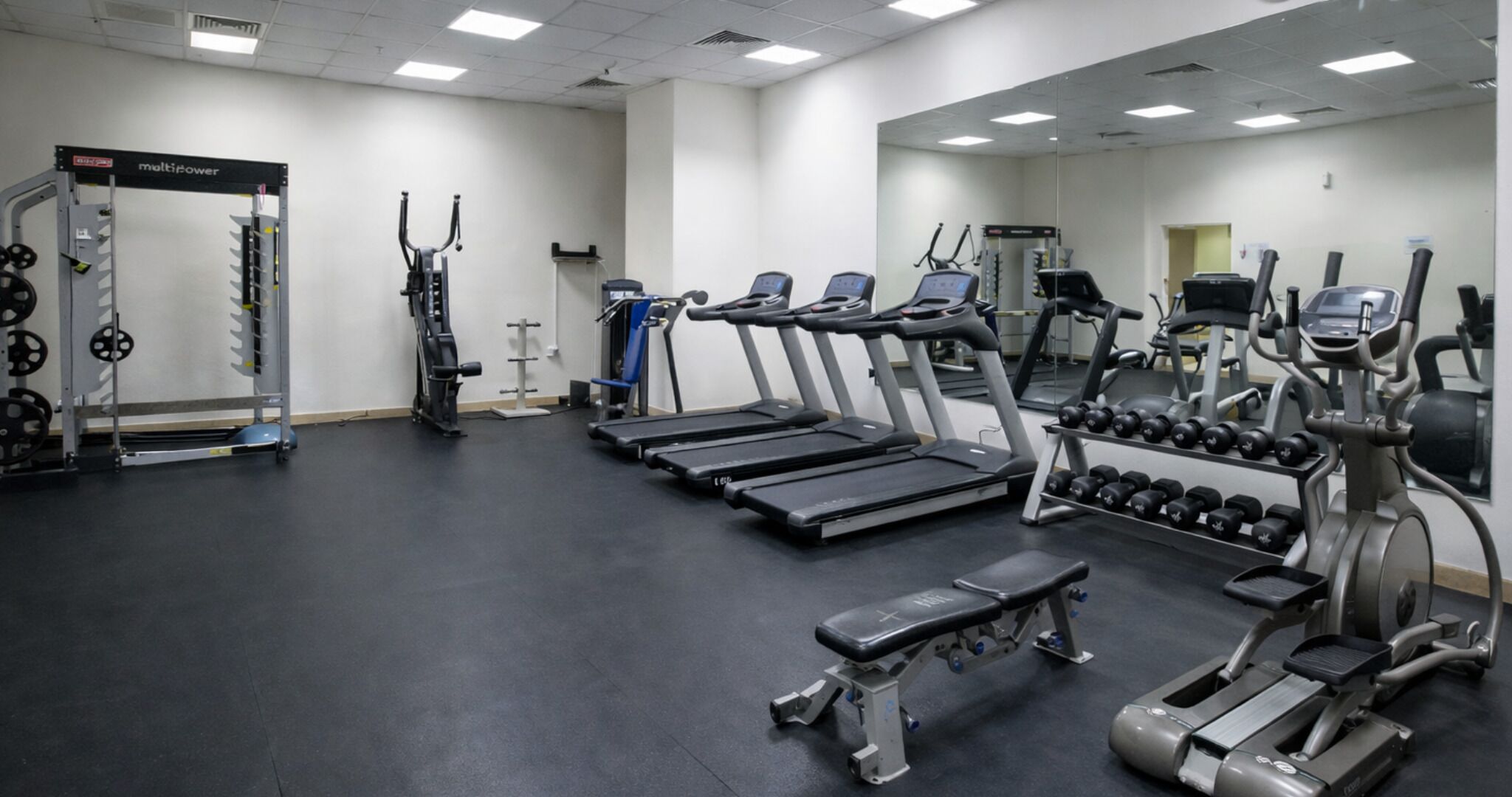 A gym with treadmills, weight machines, and dumbbells.