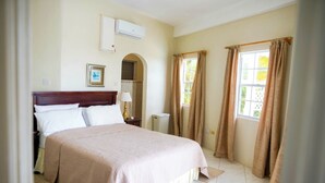 Camera da letto con un letto, un comodino, una lampada, un condizionatore d'aria e una finestra con tende.