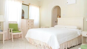 Une chambre à coucher comprenant un lit, une chaise, une commode, un miroir et une porte en arc de cercle.