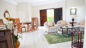 Un salon spacieux comprenant un coin repas, un ensemble de canapés, une table basse et une grande fenêtre offrant une belle vue.