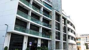 A multi-story building with a modern architectural design, featuring balconies and large windows. - Bright Studio with Rooftop Pool & Gym (Dubai)