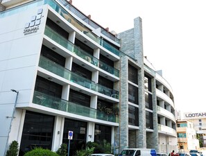 A multi-story building with a modern architectural design, featuring balconies and large windows. - Bright Studio with Rooftop Pool & Gym (Dubai)