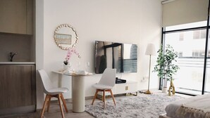 A modern hotel room with a dining area, a large window, and a bed. - Bright Studio with Rooftop Pool & Gym (Dubai)