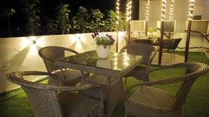 Een terras met rieten meubels, een glazen tafel en een bloempot.
